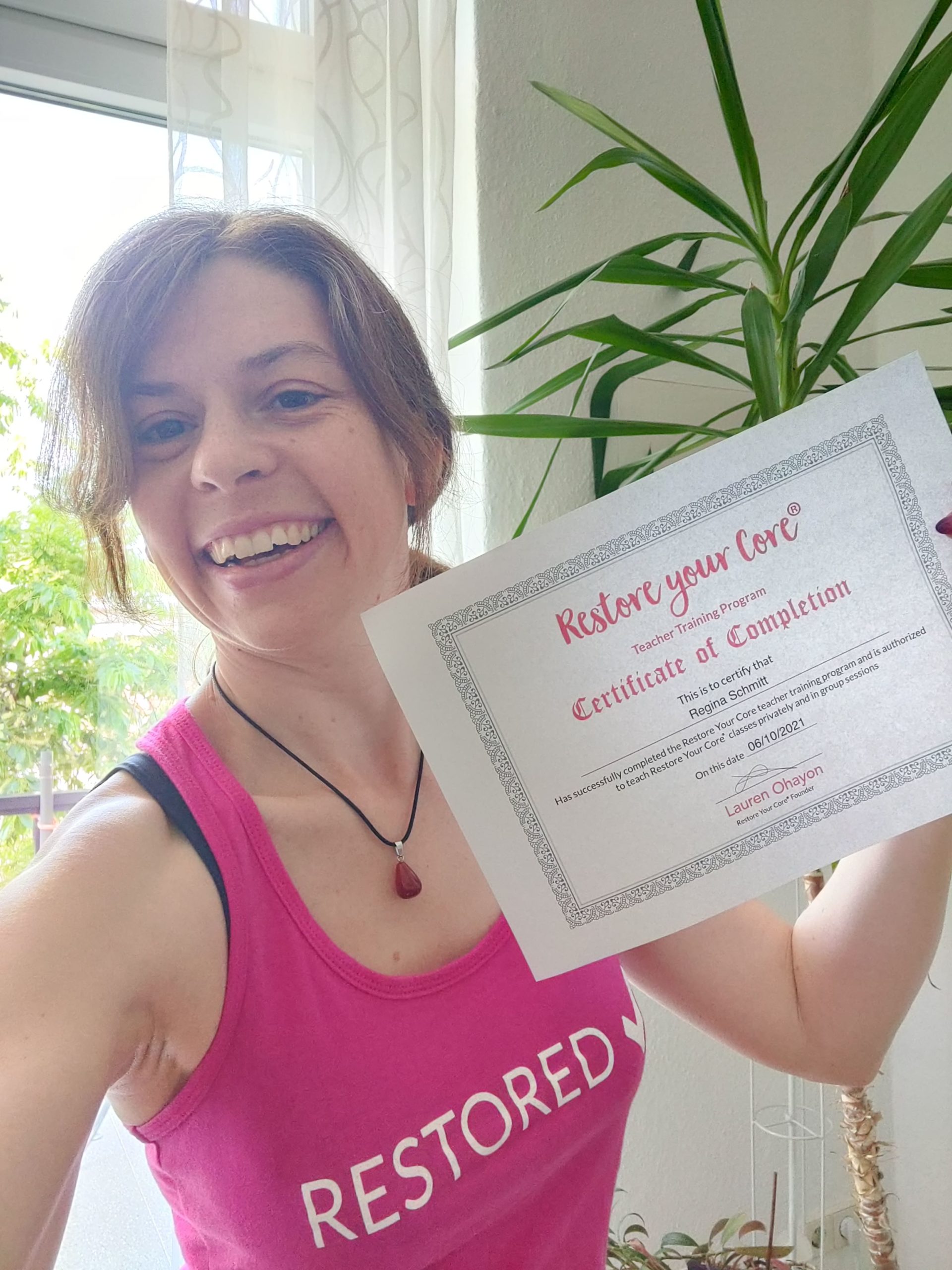 Regina Schmitt hält ihr Zertifikat der Restore Your Core Trainer Lizenz in den Händen
